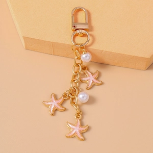 Detailed macro view of pink starfish pendants with white pearls on a gold keychain link