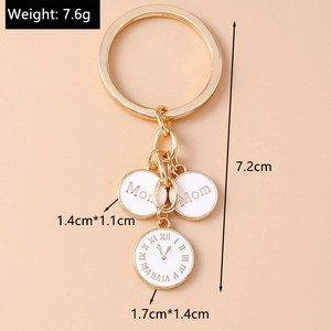 Détail du porte-clés doré Mom avec des breloques en émail blanc et un pendentif horloge