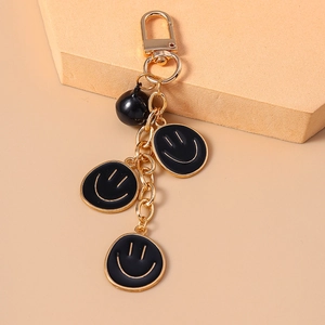 Dettaglio del portachiavi con faccine sorridenti, pendenti in smalto nero e gancio oro
