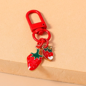 Detailed close-up of strawberry charms and red spring clasp on light orange background