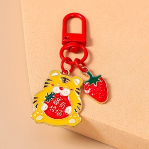 Détail d'un porte-clés tigre mignon avec breloque fraise et gravure créative rouge