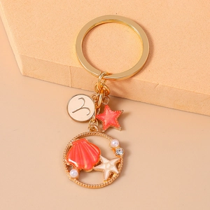 Detail of Aries zodiac sign charm with starfish and shell accents on gold keychain
