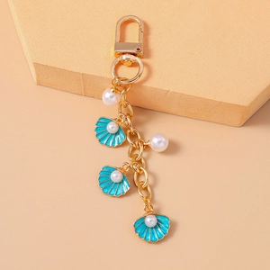 Detailed macro shot of light blue enamel shell keychain with white imitation pearls