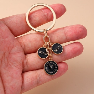 Porte-clés horloge dorée Mom avec trois pendentifs ronds sur fond rose minimaliste