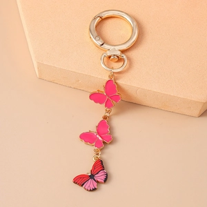 Vue détaillée du fermoir doré avec trois pendentifs papillons en émail rose et rouge