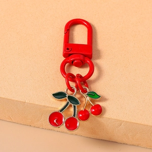 Close-up of red cherry keyrings with metal lobster clasp and green leaf charms