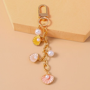 Detail view of ocean-style keychain with pink shells, pearls and golden lobster clasp