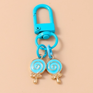 Close-up of sky blue lollipop keychains with gold metal trim on orange background