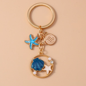 Close-up of golden keychain with starfish shell charms and Scorpio zodiac coin detail
