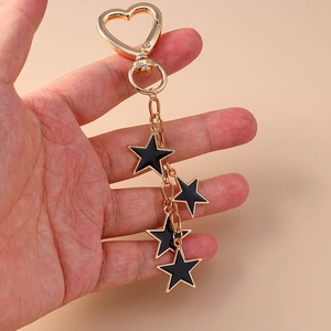 Star keychain with black enamel pentagram pendants and golden heart clasp on hand