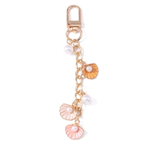 Cartoon starfish shell keychain with pearls and golden sea life charms on white background