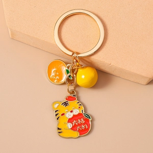 Détail du porte-clés tigre doré avec pendentif orange émaillé et clochette porte-bonheur