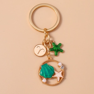Close-up of golden Aries keychain with starfish pendants and a pearl shell charm