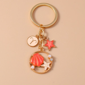 Detail of gold keychain with Aries zodiac sign, starfish, shell charms and pearls