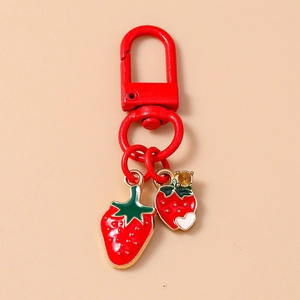 Detailed view of red metal keychain with strawberry pendants and white heart charm