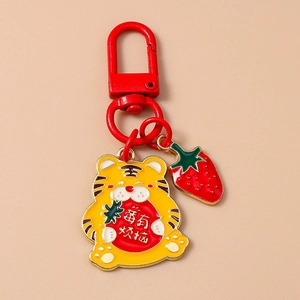 Détail du porte-clés tigre de dessin animé avec breloque fraise et crochet rouge