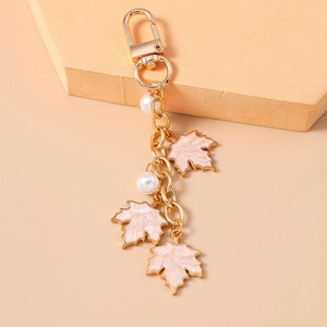 Close-up of golden maple leaf keychain with pink enamel pendants and white pearls decoration