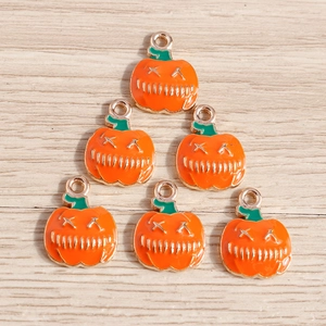 Vue détaillée de 6 breloques citrouilles d'Halloween en émail sur fond de bois