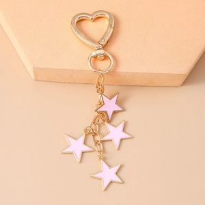 Detail view of golden heart-shaped clasp and pink star pendants on a keychain