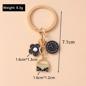 Close-up of golden keychain with camellia flower, clock charm, and quilted bag detail