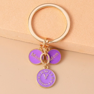 Détail d'un porte-clés doré avec pendentifs violets Mom et breloques horloge romaine