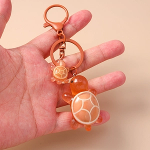 Detail of cute orange resin mother and child turtle keychain with white grid patterns