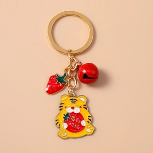 Détail d'un porte-clés tigre mignon avec pendentif fraise et clochette rouge sur rose