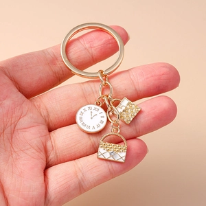 Golden keychain with cartoon clock, quilted handbag pendant, and flower accessory on hand