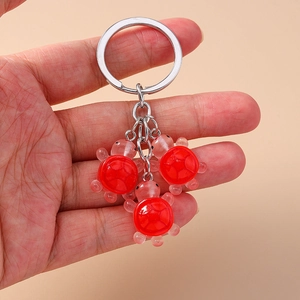 Porte-clés tortue en résine rouge avec trois petits pendentifs sur un anneau argenté