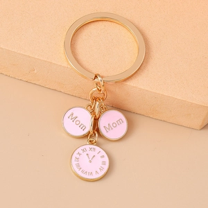 Détail d'un porte-clés doré avec pendentifs Mom en émail rose et breloques horloge