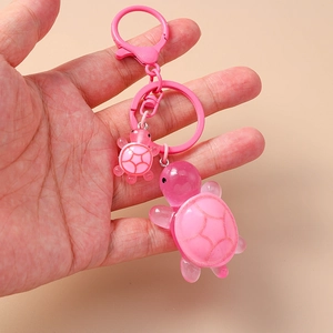 Detail of pink resin turtle keychain set with lobster clasp and metal ring hand-held