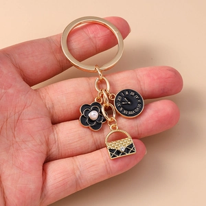 Golden keychain with black flower, roman clock, and quilted handbag pendants