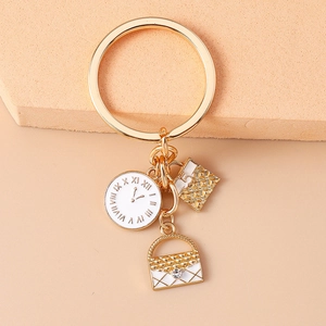Detail of golden keychain with mini quilted handbag, clock charm and elegant pearl accents