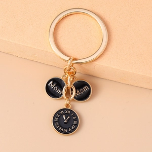 Vue détaillée du porte-clés doré MOM avec charms horloge en émail noir pour sac à main