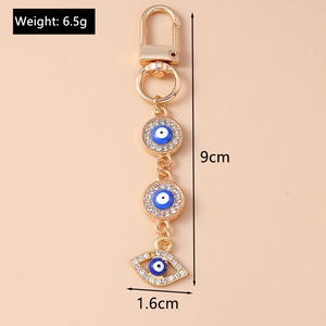 Detailed view of evil eye keychain with gold metal plating and dimensions 9cm by 1.6cm