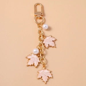Detail of pink maple leaf charm with white pearls on a golden keychain accessory