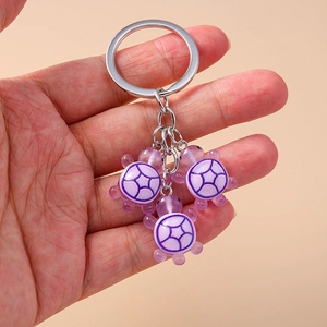 Vue détaillée de trois breloques tortue en résine violette sur un porte-clés argenté