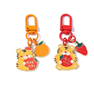 Détail de porte-clés tigre mignon avec breloques fraise et orange en émail