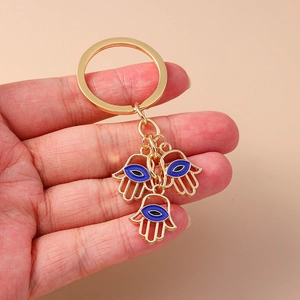 Detailansicht goldener Hamsa-Hand-Schlüsselanhänger mit blauen Evil Eye-Anhängern