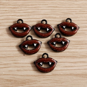 Détail de breloques lèvres de vampire en émail rouge scintillant pour création de bijoux