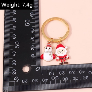 Detail view of Christmas snowman and Santa enamel keychain with size ruler measurement
