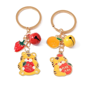 Détail de porte-clés tigre de dessin animé avec breloques fraise et orange et anneau doré