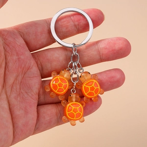 Détail du porte-clés tortue avec trois breloques orange en résine et anneau argenté
