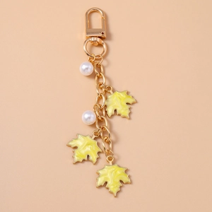 Detailed view of golden maple leaf charms with pearl accents on a keychain accessory