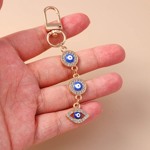 Golden Evil Eye keychain with sparkling crystals and star motifs on pink background