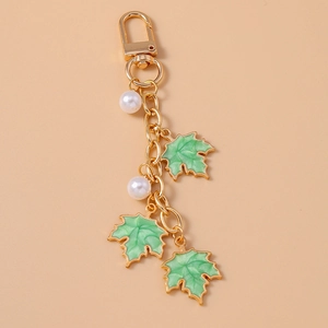 Detail view of green maple leaf keychain with white pearls and golden lobster clasp