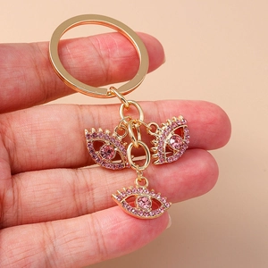 Nahaufnahme von goldenem Schlüsselanhänger mit drei rosa Kristall-Evil-Eye-Anhängern