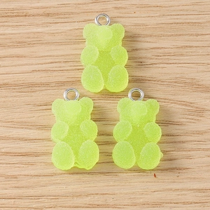 Detailed macro view of three light green resin gummy bear charms with sugar-like matte texture