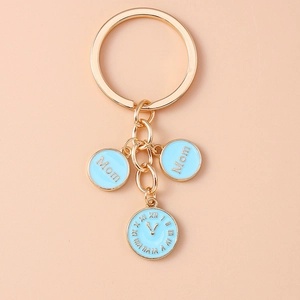 Détail du porte-clés en métal doré avec breloques Mom en émail bleu clair et pendentif horloge
