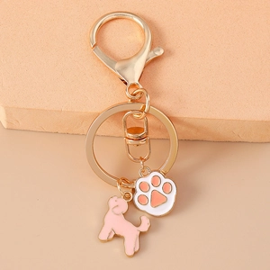 Gros plan d'un porte-clés doré avec silhouette de chien rose et breloque patte